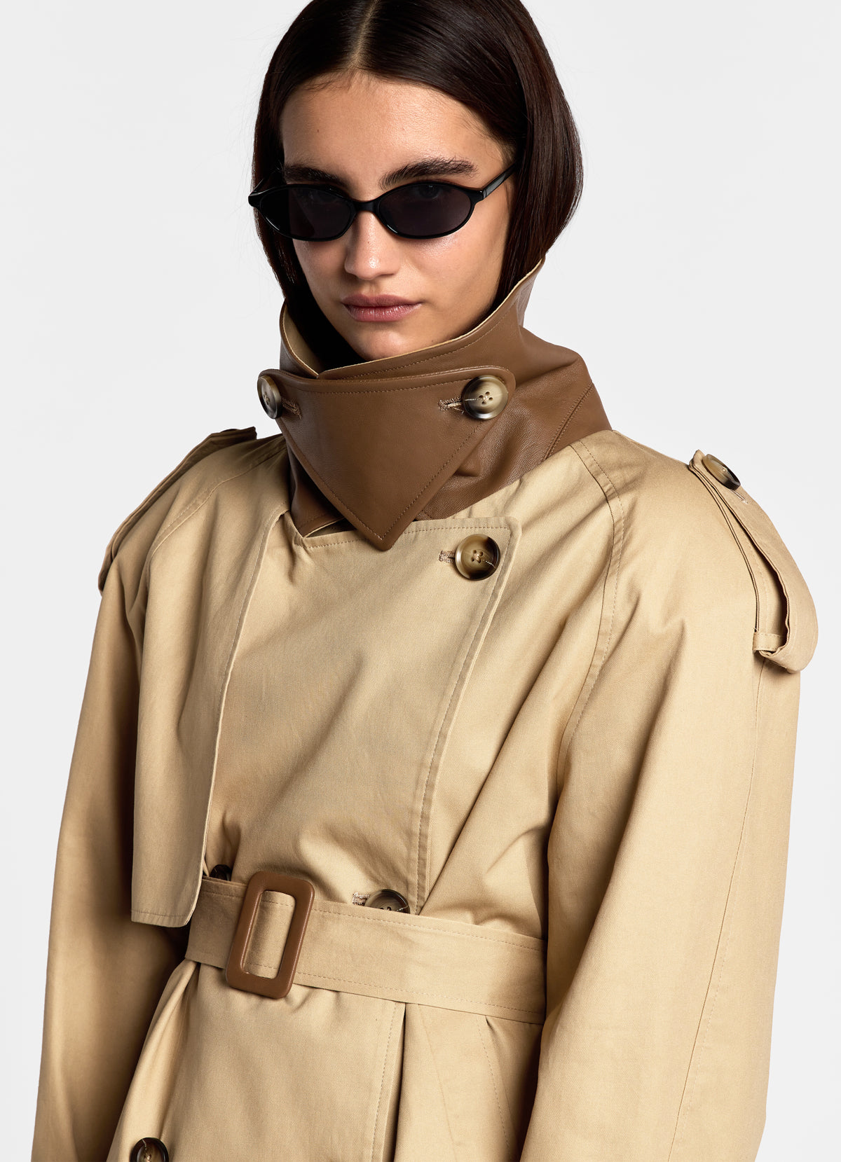 Close up of model in cotton trench coat with collar up revealing leather trim underneath.