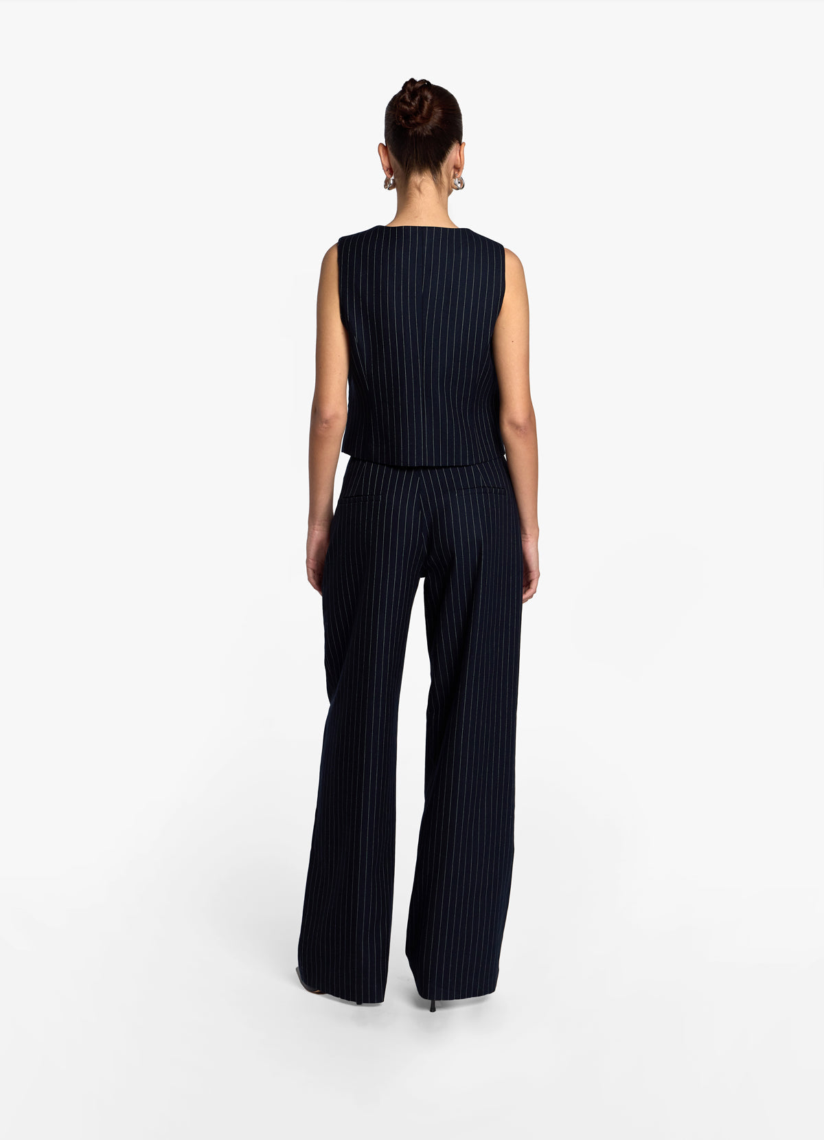 Back view of model wearing navy pinstripe suit trousers showing length against a white background.